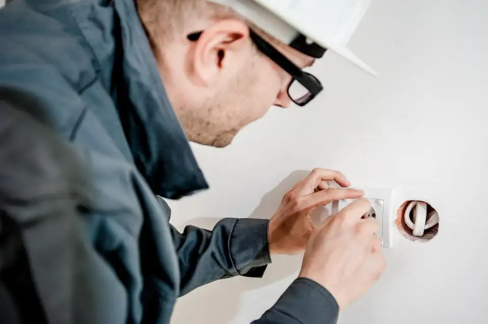 An electrician working on a wall outlet